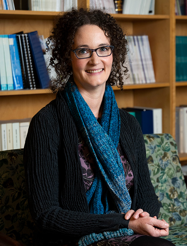 Price sits in front of a bookcase.
