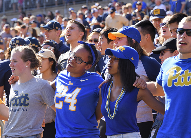 students in the stands at last year's homecoming football game with arms around each other