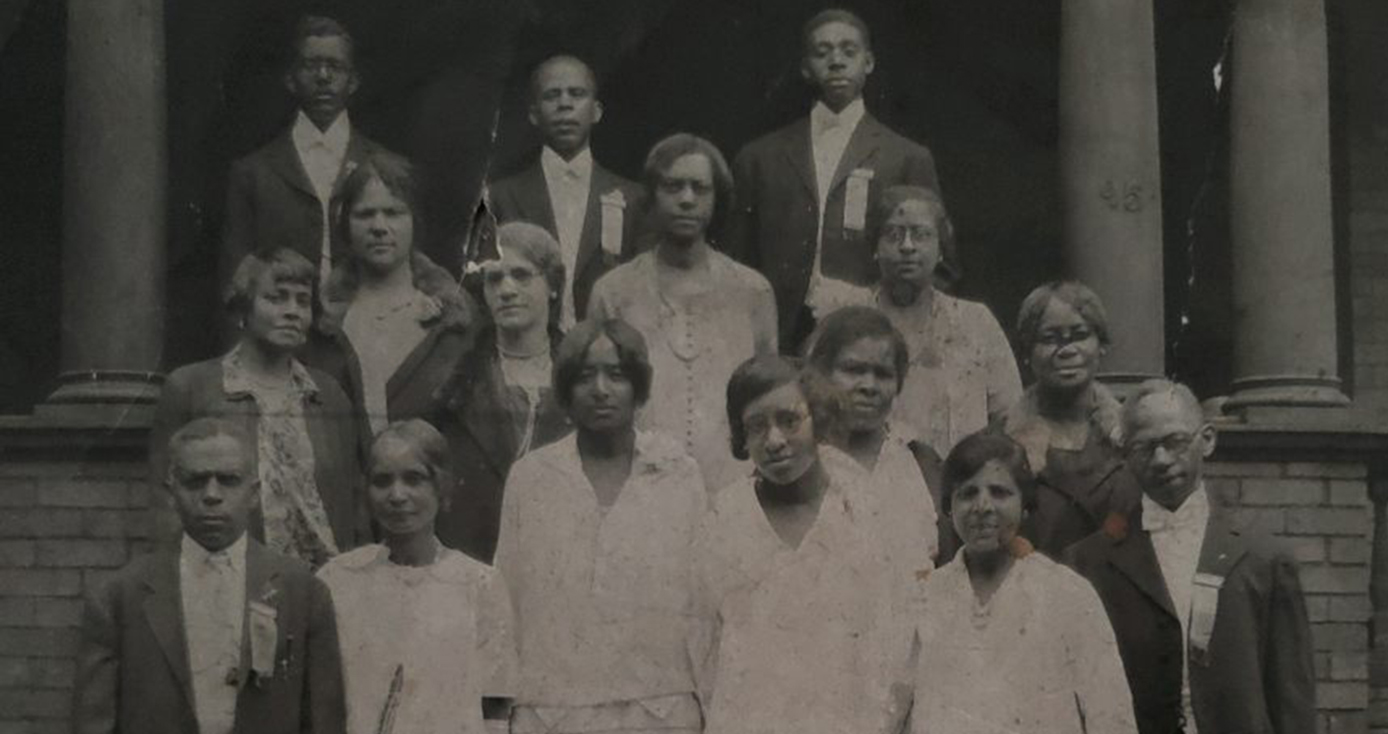 A black and white group photo including Isma Burrell on the steps of a church building