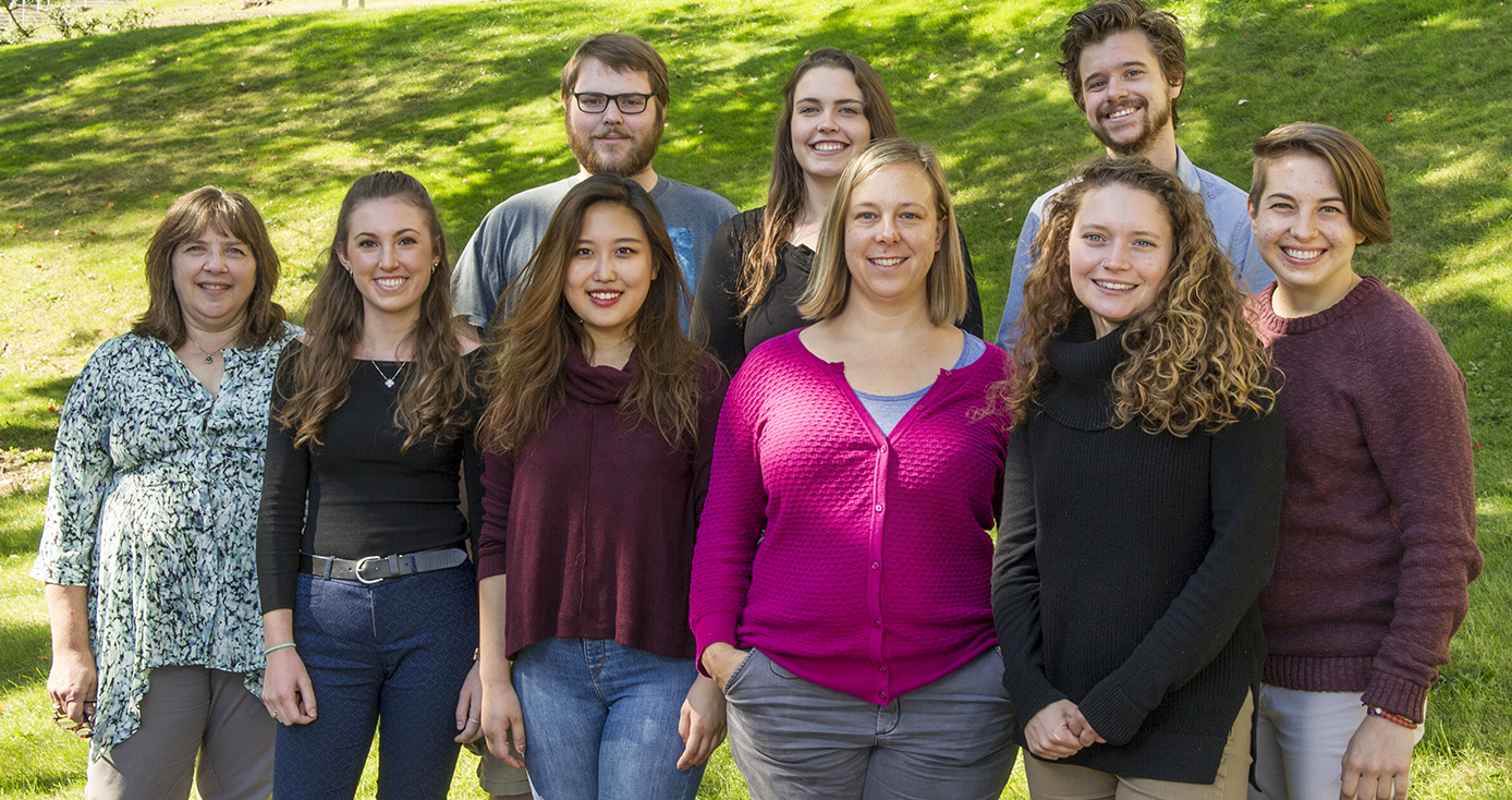 The Roecklein lab standing at the base of a bright green grassy hill