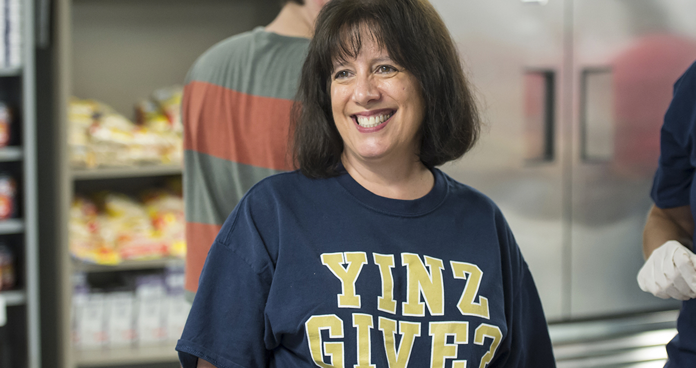 woman in blue and gold "Yinz Give?" shirt