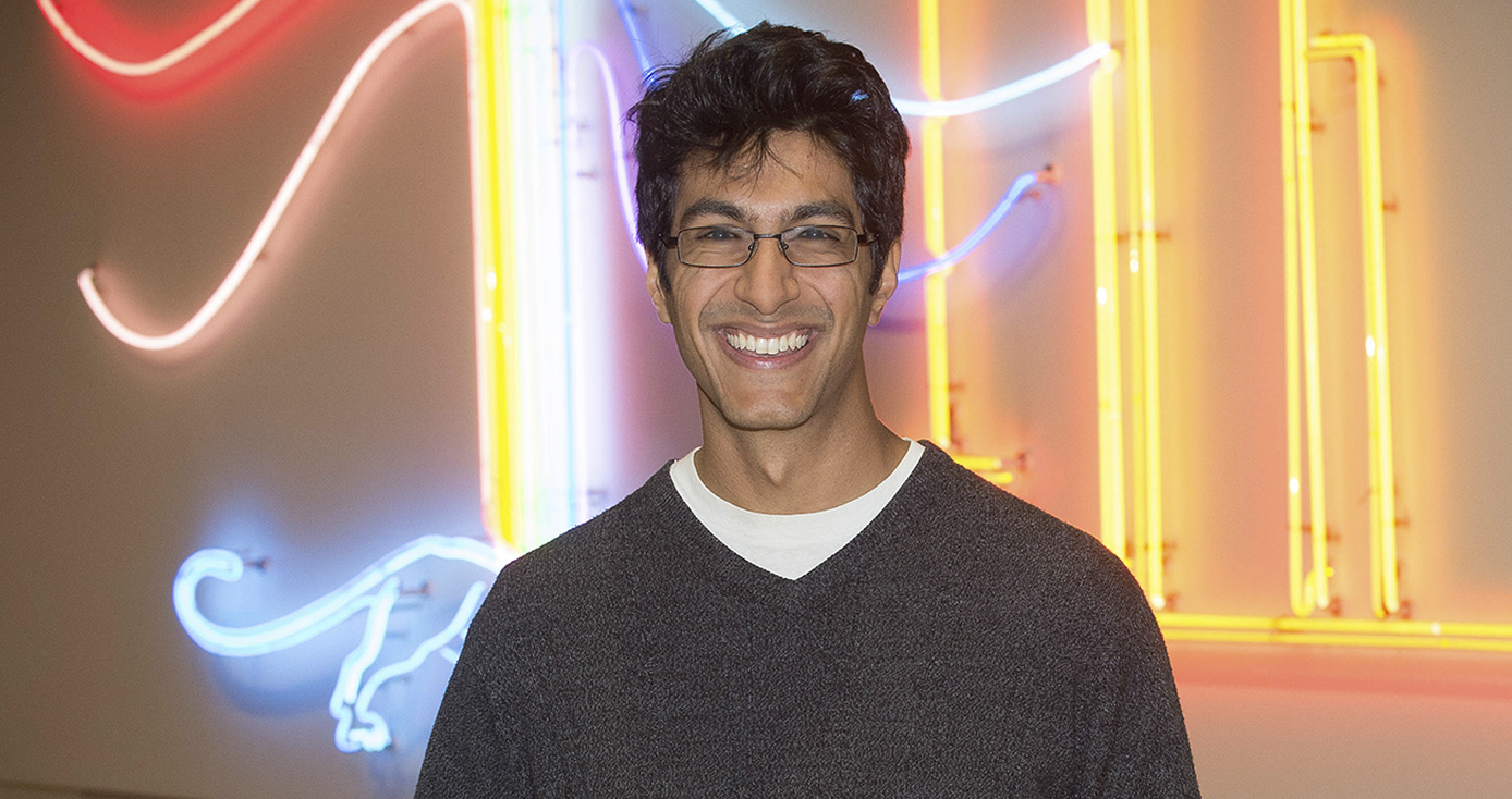 Samir Lakhani standing in front of a colorful neon wall display