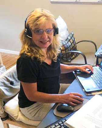 Kuchar in a headset, wearing a dark top, sitting at her desk