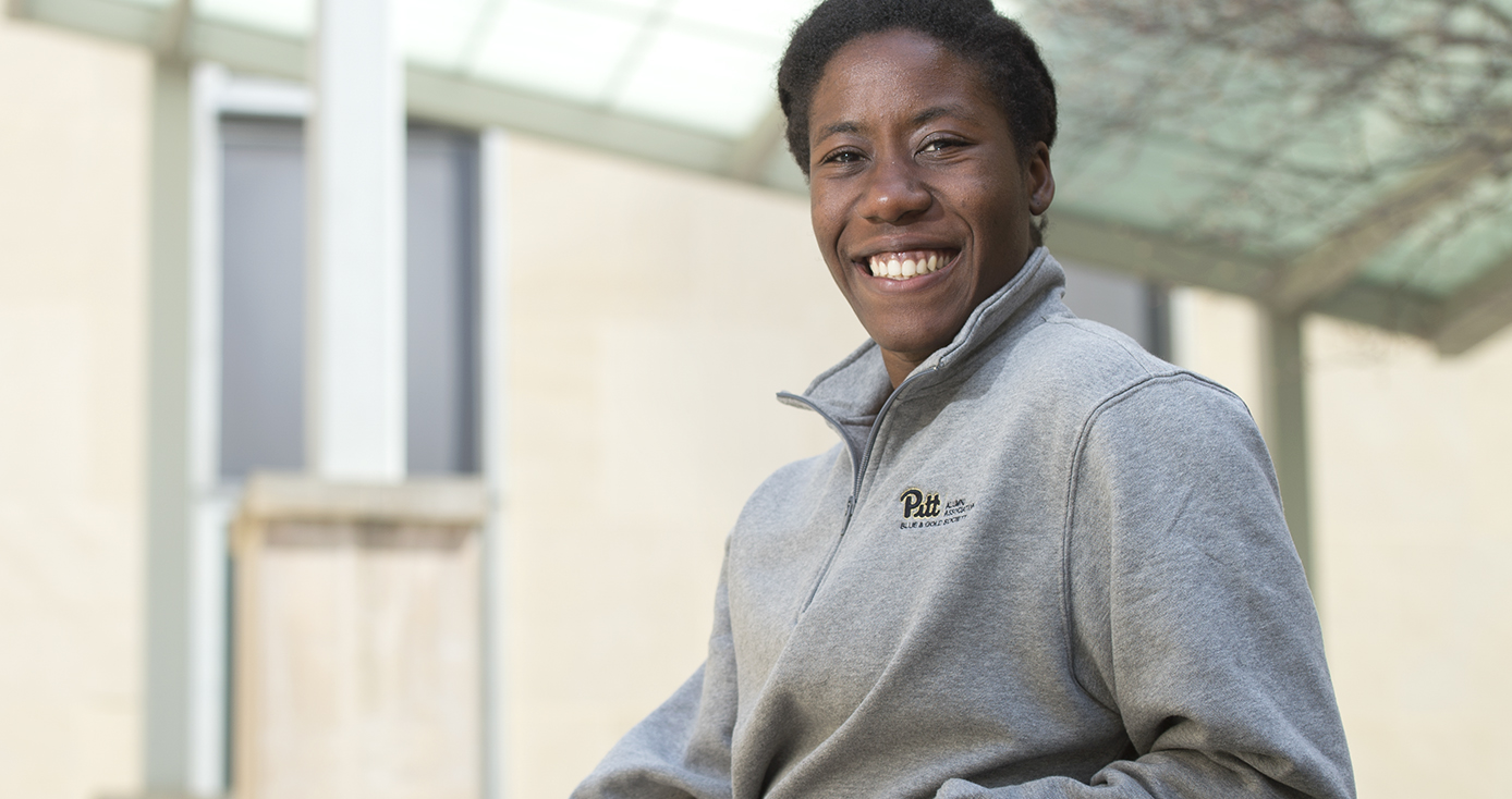 Andin Fosam headshot wearing gray zip-front sweatshirt with Pitt script logo