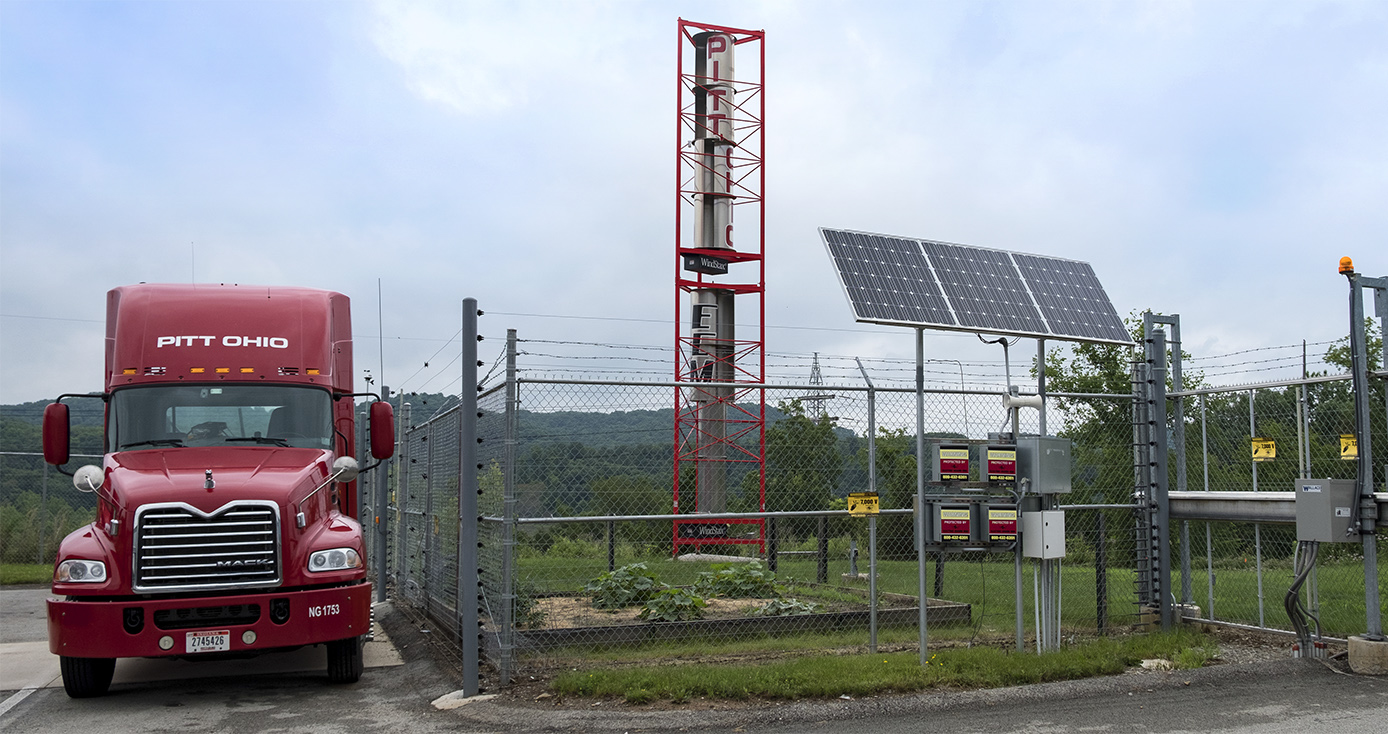 Red tractor trailer parked beside solar and wind power facilities