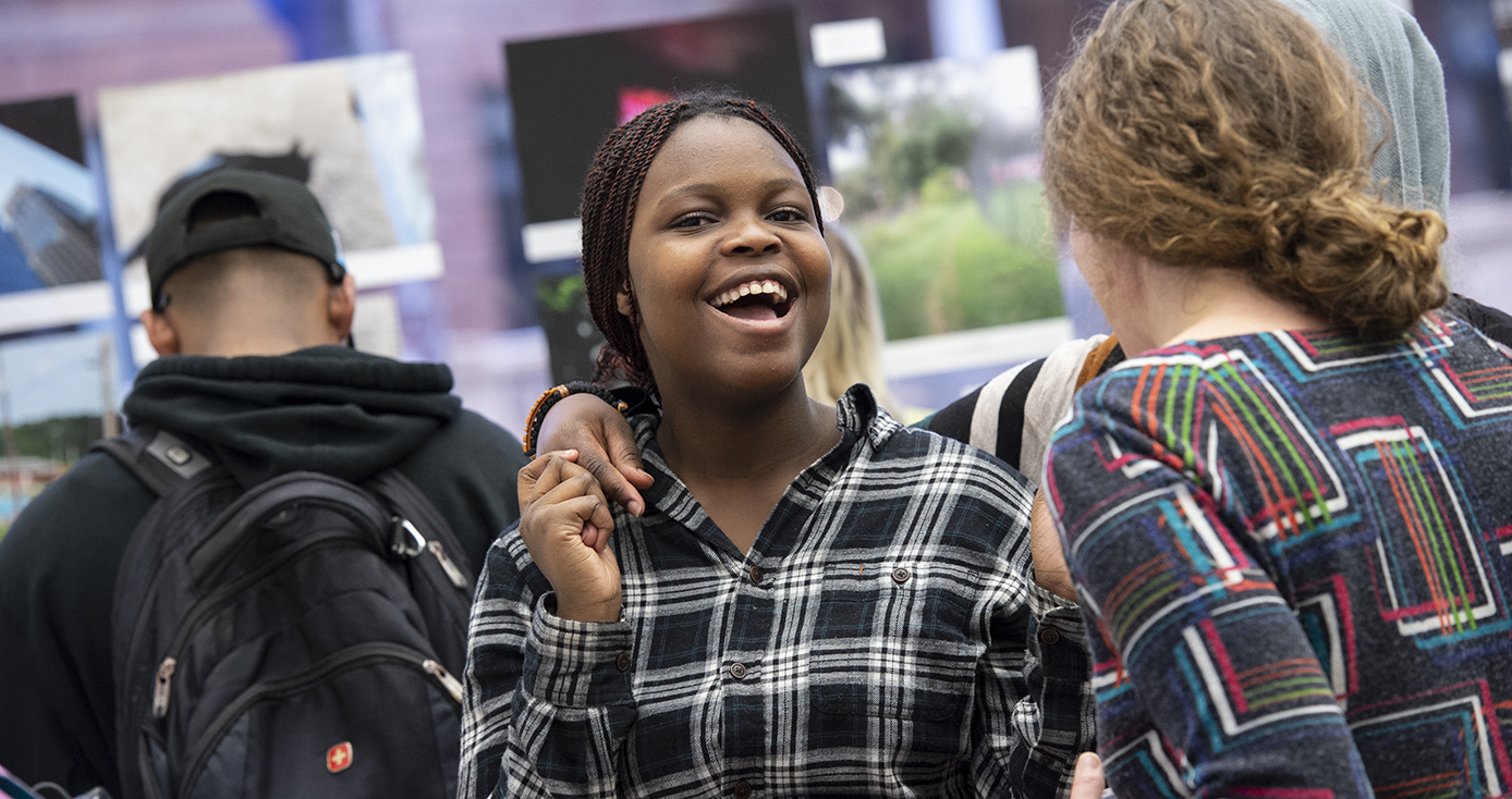 Tomi in a black and white plaid shirt laughing at the exhibit
