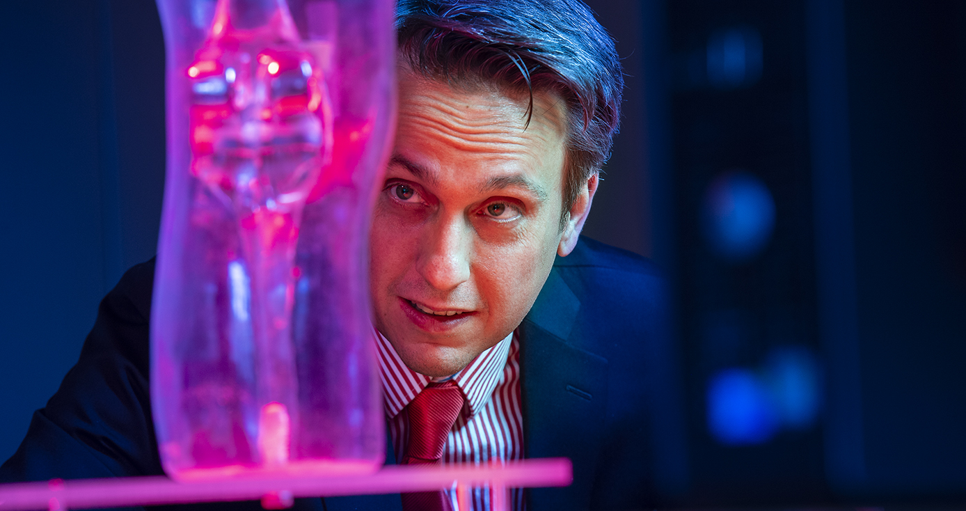 Sejdic looking at a pink-light-illuminated replica knee