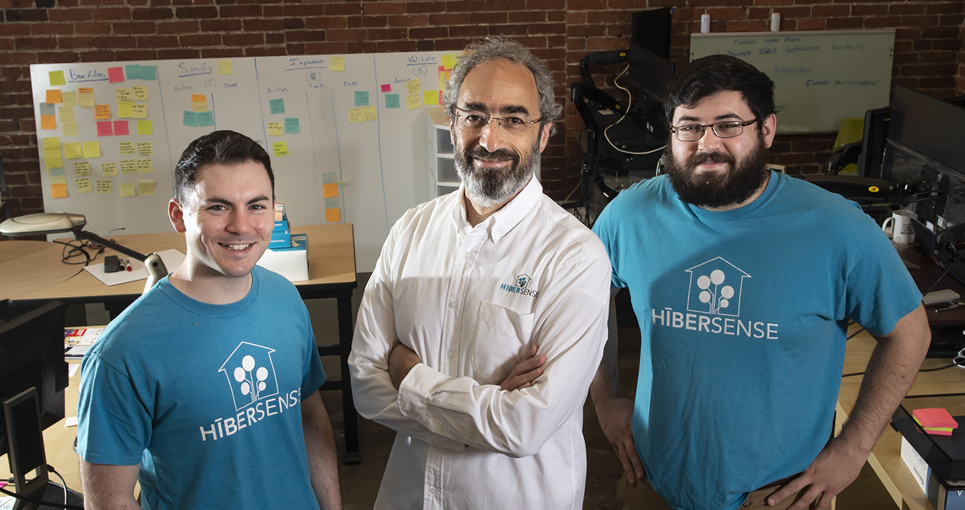 three men standing confidently together, two in Hibersense branded t-shirts