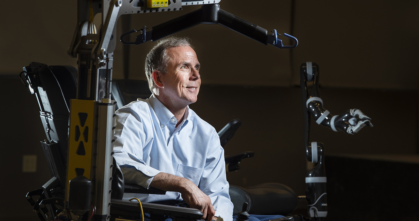 A man in a light blue shirt leans on a machine