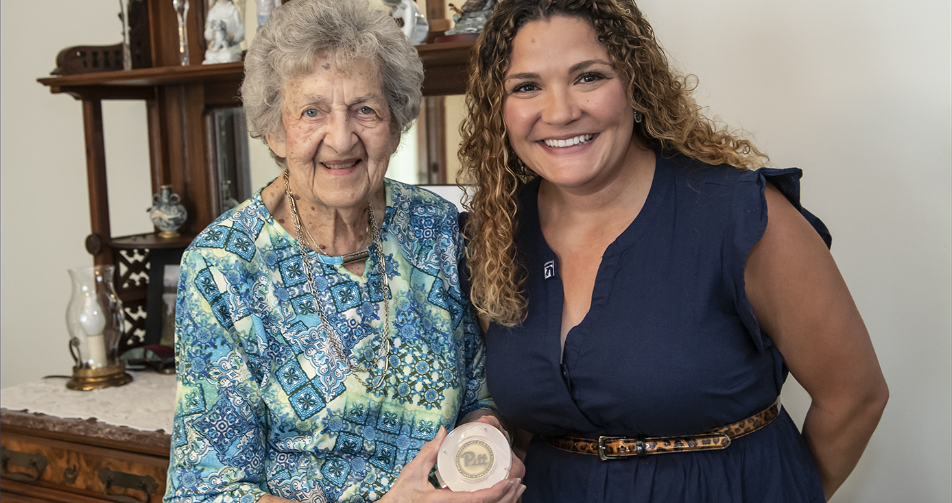 Jean in a blue and green blouse holding the challenge medal with Berringer in a blue dress next to her