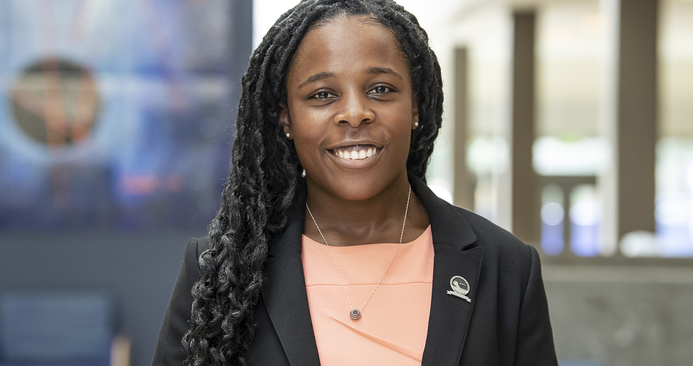 Kathy Monangai portrait, standing in front of pharmacy building at Pitt