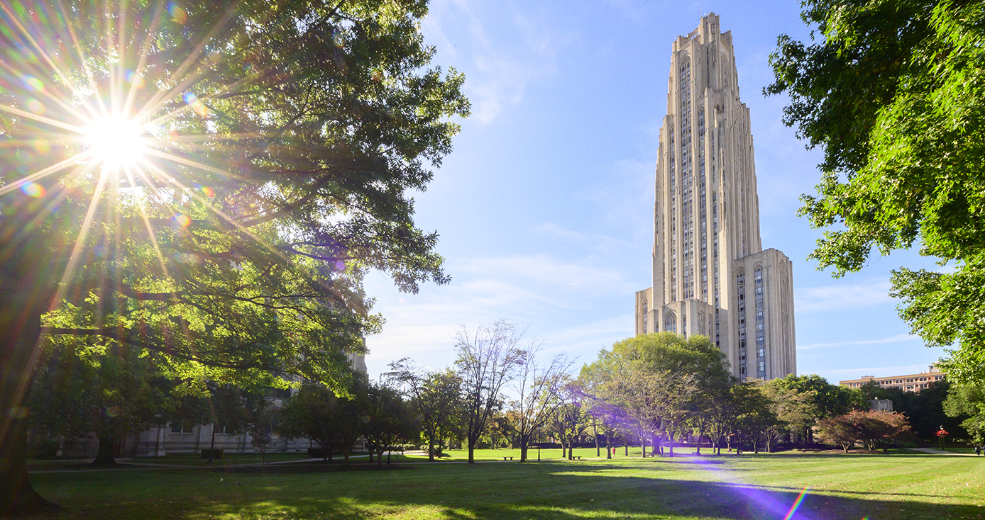 The Cathedral of Learning behind trees on a sunny day