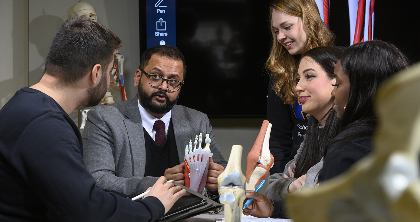 Five people sit around a table, discussing