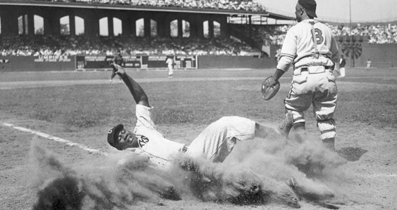 Josh Gibson sliding home in a baseball uniform