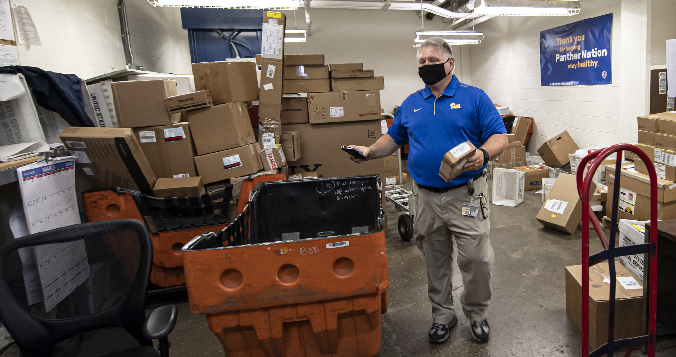 A Pitt staff member in a blue shirt in the mailroom