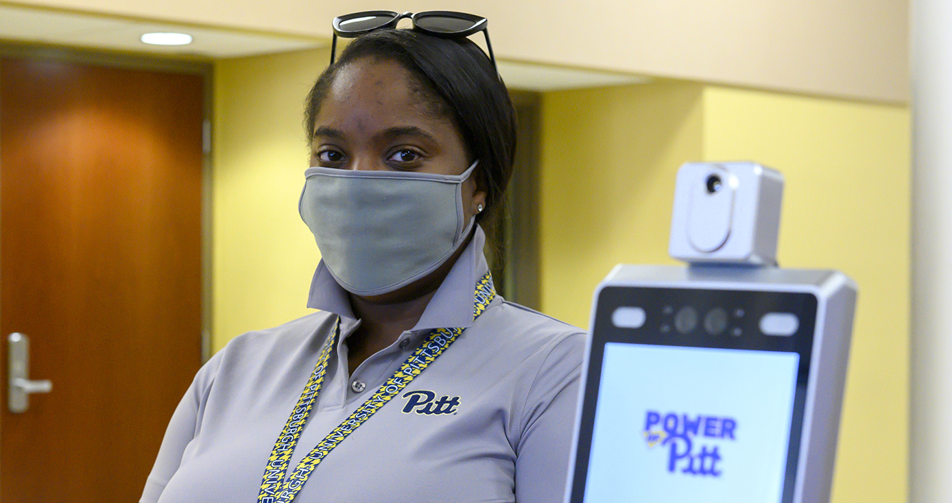 A person in a face mask next to a tablet