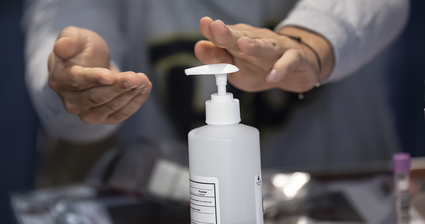 A person uses a hand sanitizer dispenser