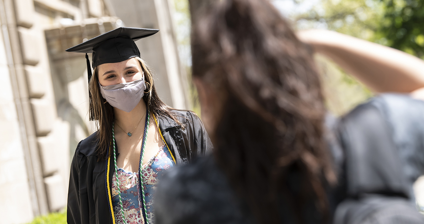 Louise Lovecchio, in graduation attire, poses for photographer and fellow Pitt student Alanna Reid, foreground, outside of the Cathedral of Learning (Aimee Obidzinski/University of Pittsburgh)