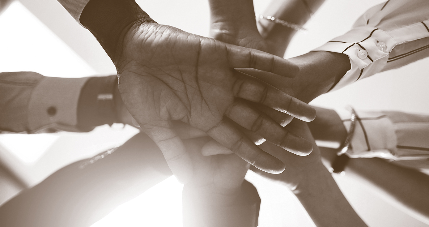 10 hands one top of one another in a black and white photograph