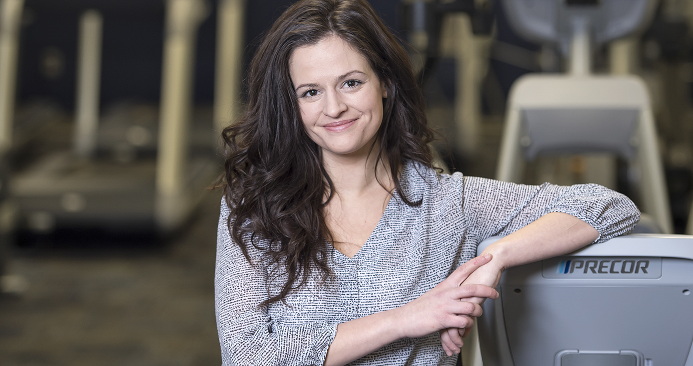 Oberlin in a printed blouse, leaning on a treadmill with her elbow