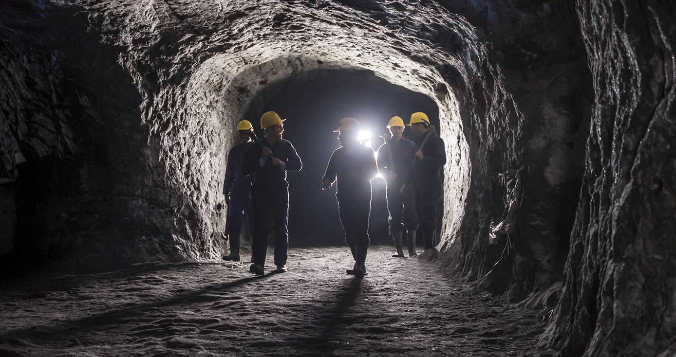 five miners in a cave with a bright light shining behind them