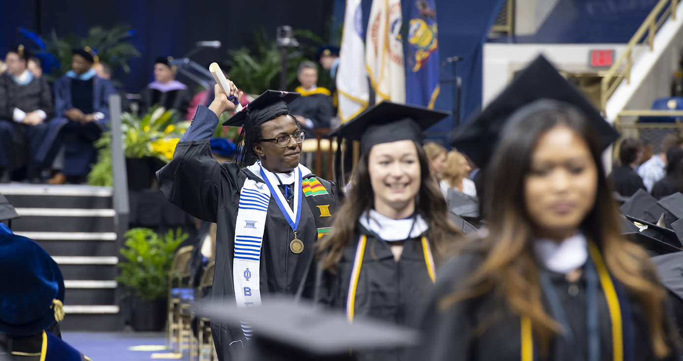 graduate holding a scroll above his head