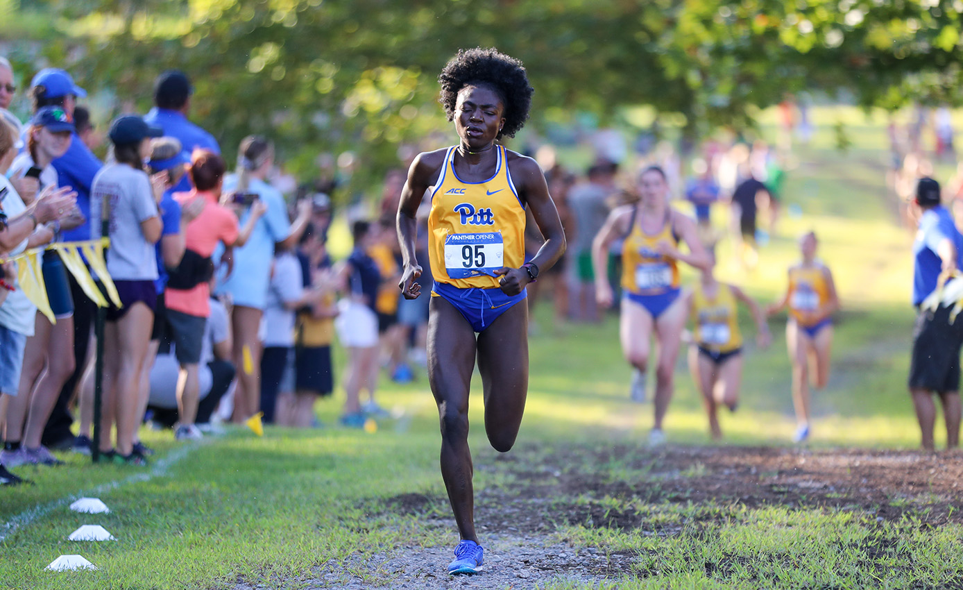 A runner in Pitt attire runs past a crowd