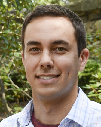 Brian Thoma headshot, with green leafy outdoor background