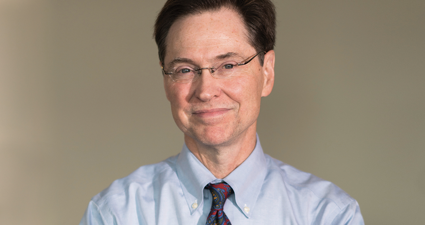 Dermody in a shirt and tie in front of a tan background