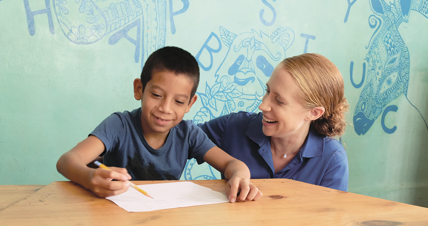 Emily Monroe with a young boy in front of a green and blue mural