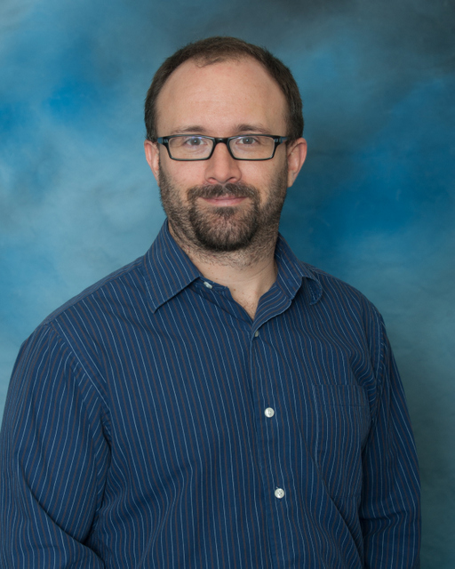 Erickson in front of a blue background in a dark blue collar shirt