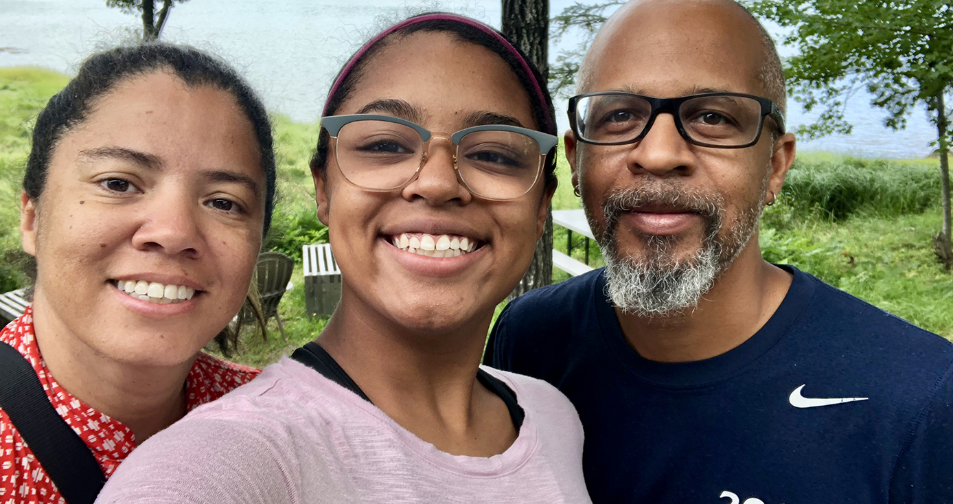 a mom, daughter and father together in front of a lake