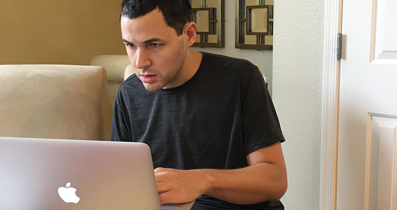 Man in a black shirt looking at a laptop