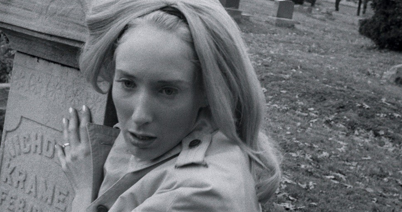 a black and white image of a woman gripping a tombstone