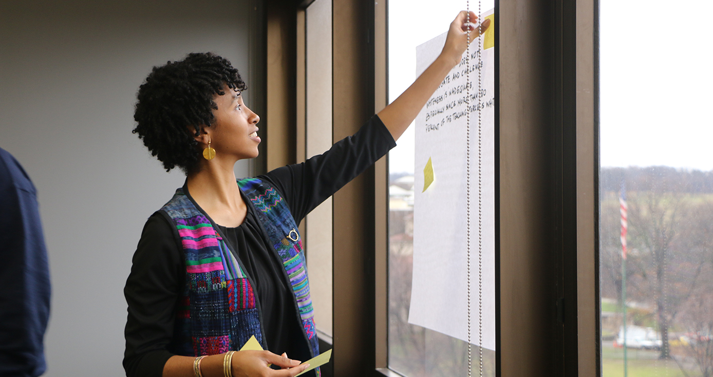 MyQuella Swogger in a black shirt posting notes onto a window