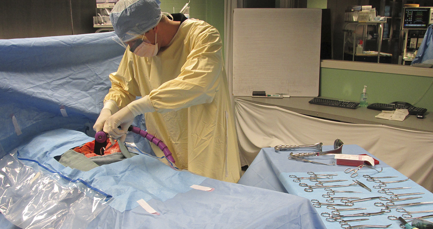 person in yellow scrubs simulating an operation with the surgical retractor system