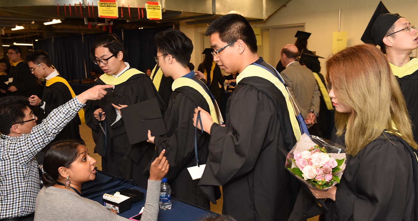 Students in graduation caps and gowns stand in line