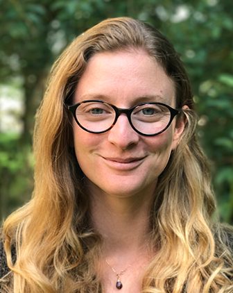 A woman in glasses with trees in the background