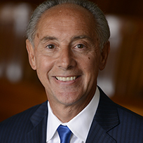 Gismondi in a dark suit, white shirt and blue tie