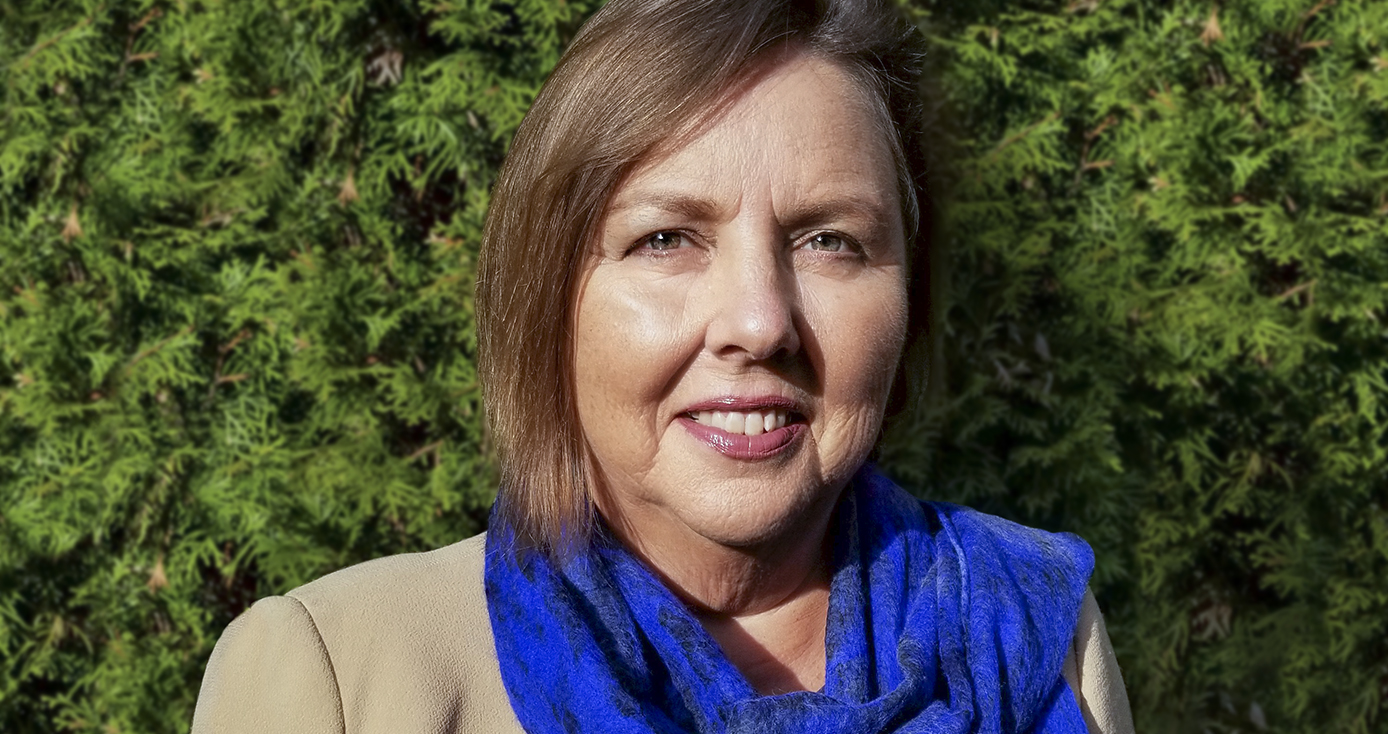 headshot of Catherine Koverola, in front of background of greenery