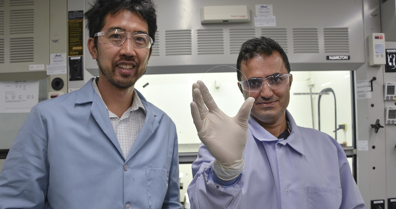 two men in lab coats, one holding a circle of glass