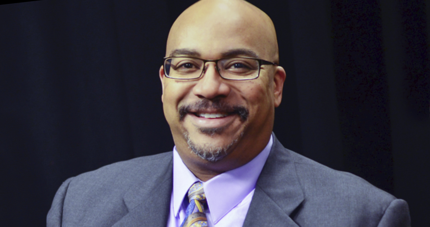 Henderson in a gray suit and purple collared shirt