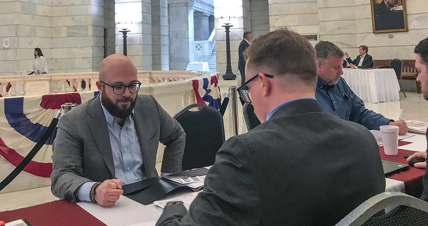 Two men in suits sitting across a table from each other