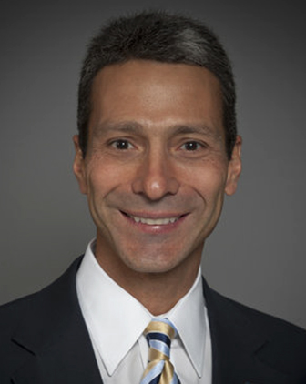 Headshot of Gregory Reed in suit jacket and tie