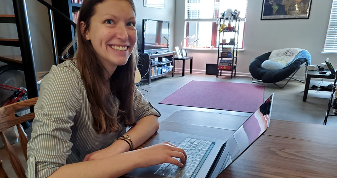 Amy Baby in a green shirt working on a laptop on a table