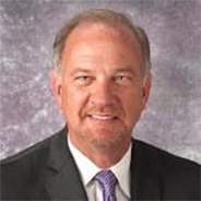 Donal Yealy in a black suit and white shirt with a purple tie