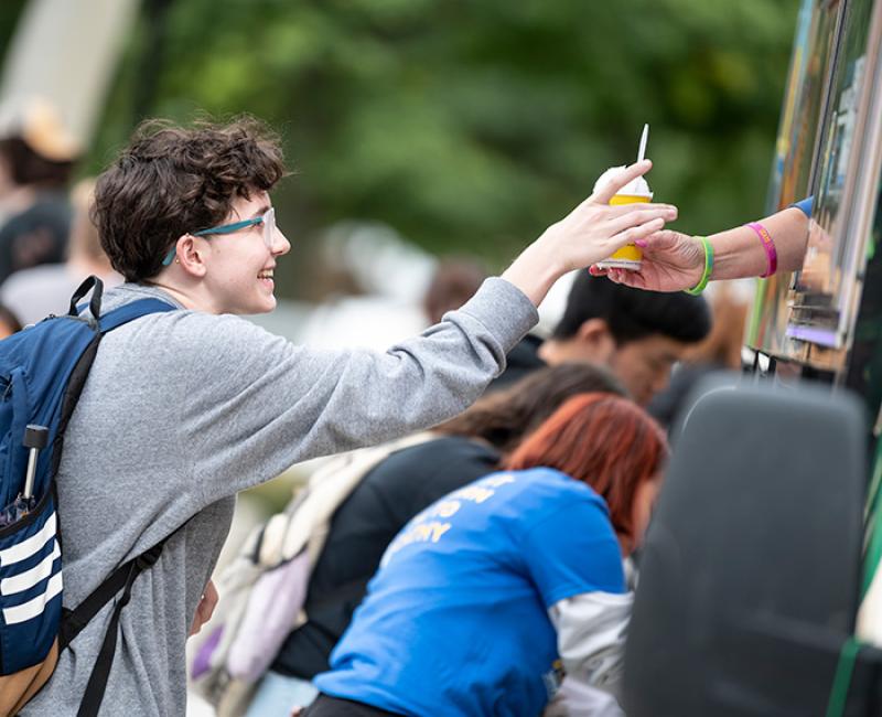 Smiling student receiving food from a food truck.