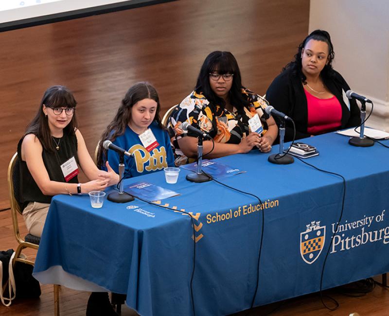 Students sit at a table as part of a panel