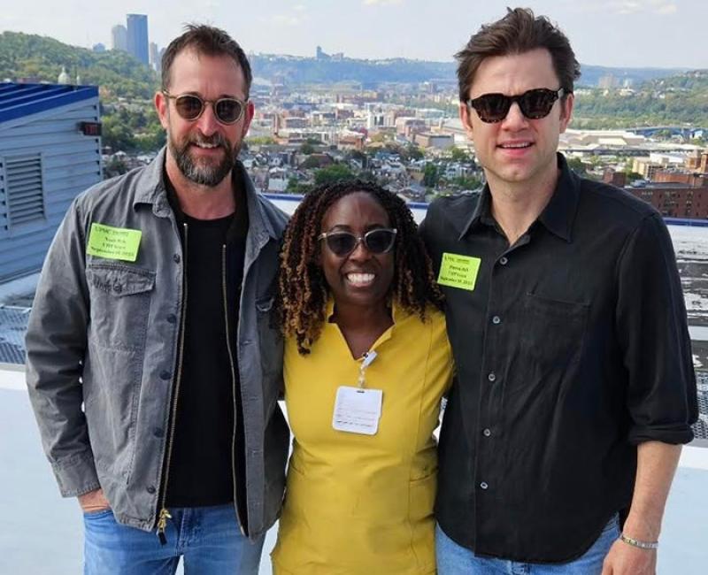 Sylvia Owusu-Ansah poses with two men with the city of Pittsburgh in the background