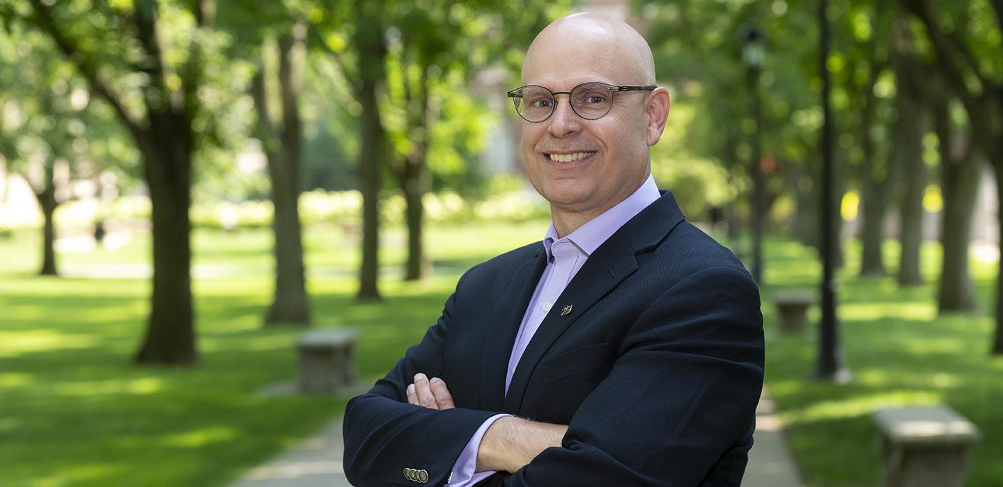 Robert K. Cunningham standing outside with arms folded, trees in background